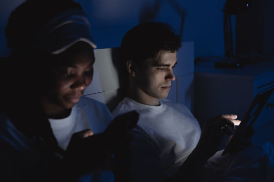 Couple sitting in bed looking at their phones in the dark.